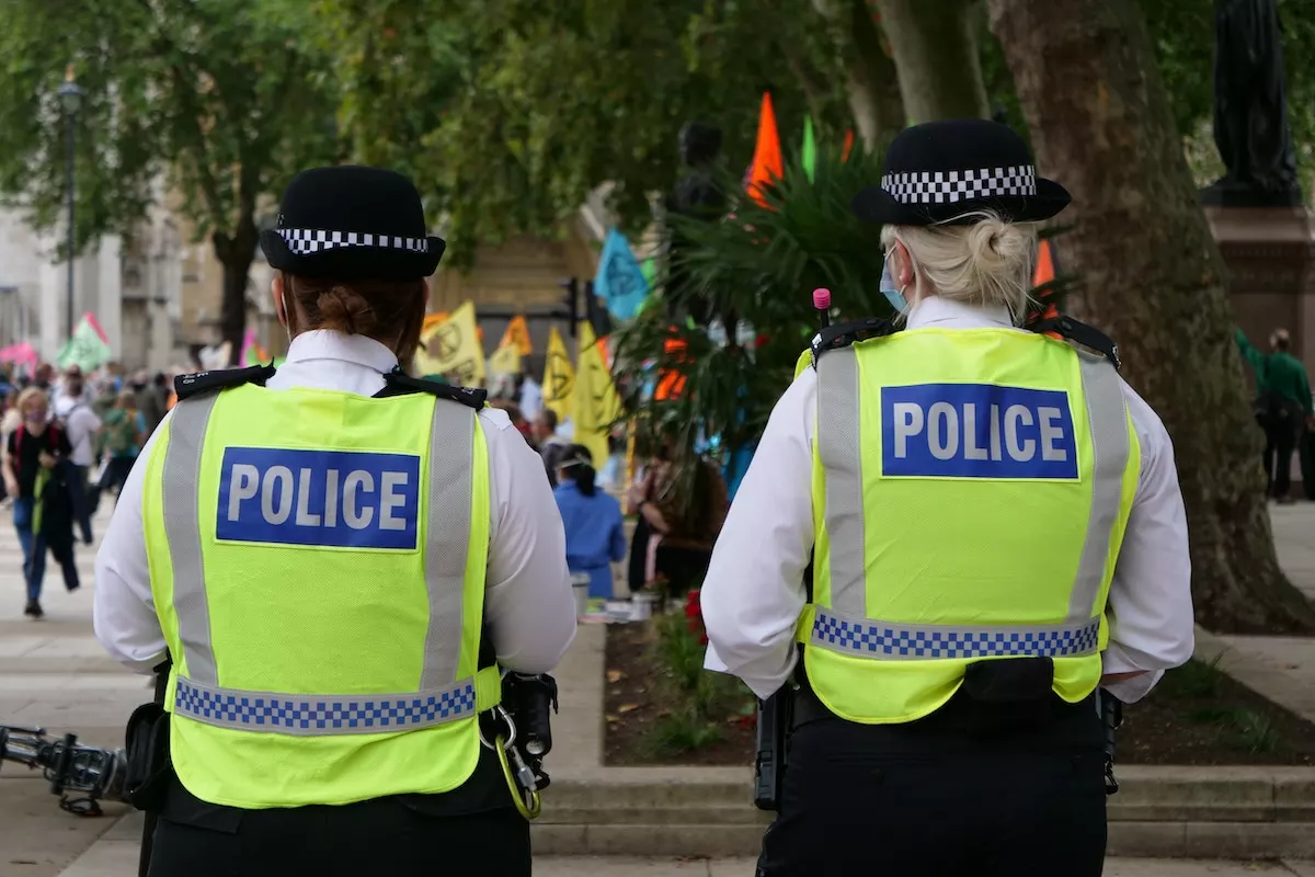 View of the backs of two female police officers wearing high vis police vests. 